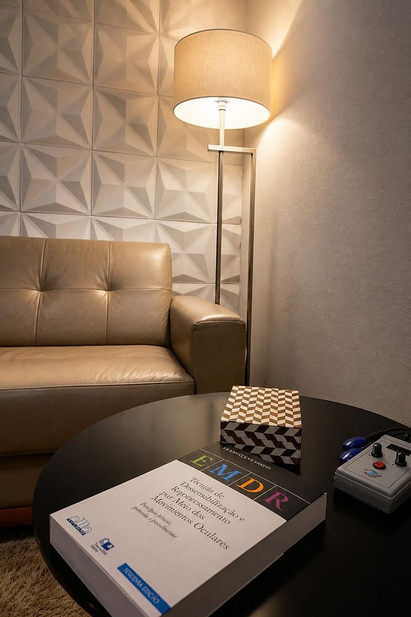Consultório: sofá, luminária e mesa de apoio com o livro de EMDR